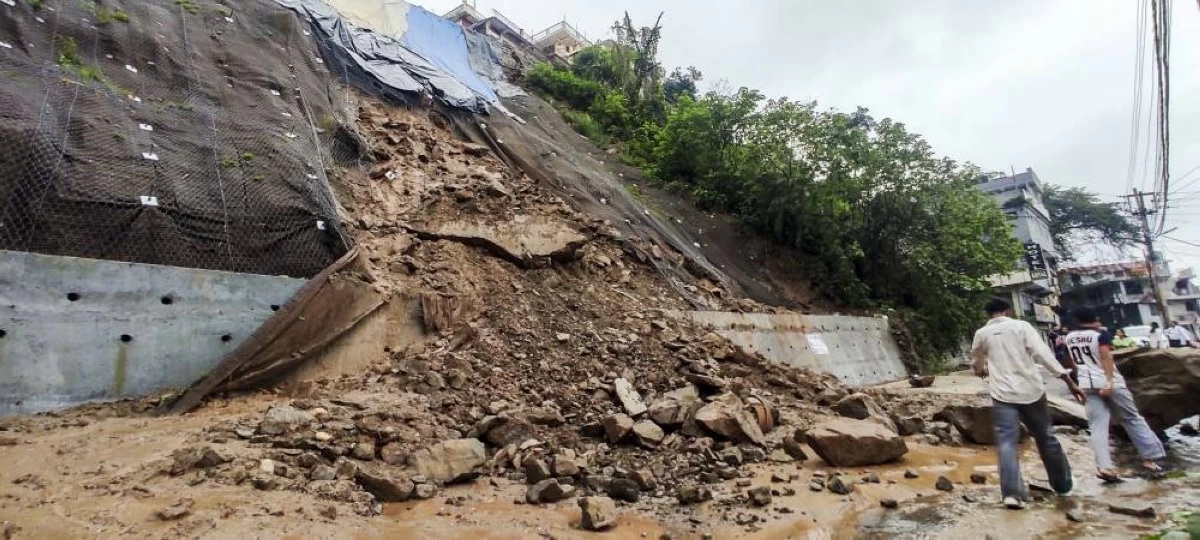 People walk past the debris lying on a road after a landslide triggered by heavy rainfall in Mandi, Himachal Pradesh on Monday (PTI image)