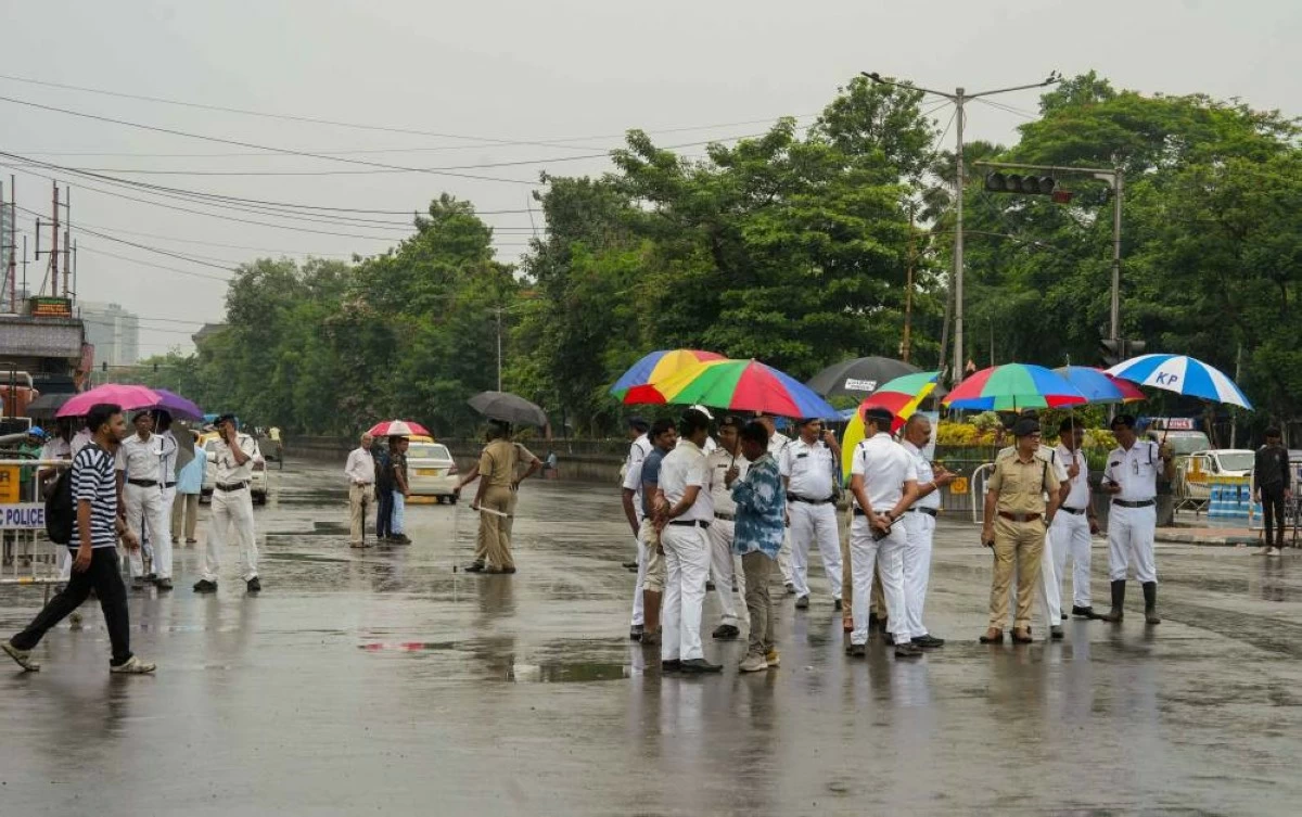 Police personnel keep vigil during rainfall amid a 24-hour nationwide general strike called by trade unions at Esplanade area in Kolkata. Ten central trade unions launched Bharat Bandh on July 9, mobilising over 25 crore (250 million) formal and informal workers across India.  (Credit: PTI)