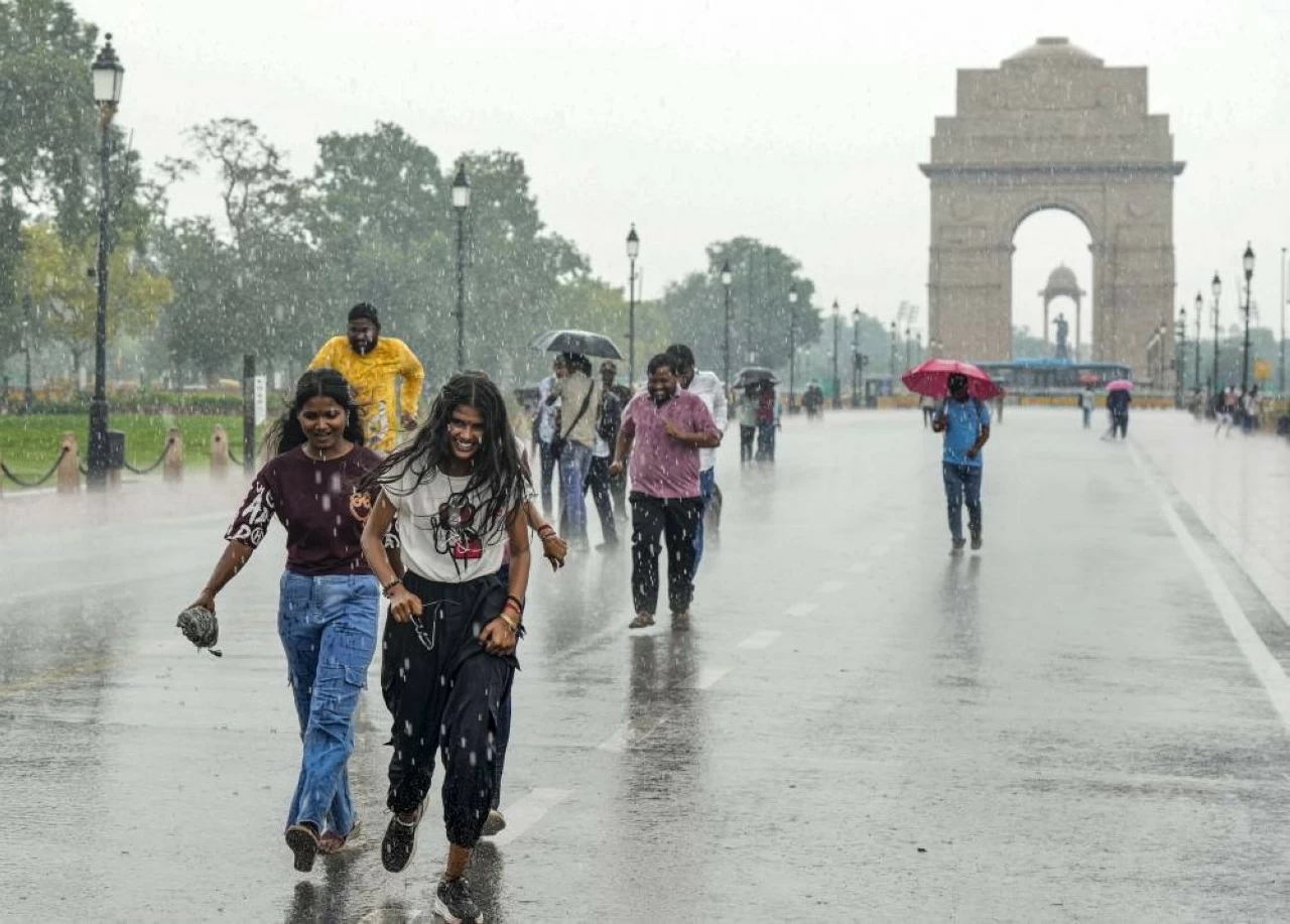 Pedestrians during rainfall, at Kartavya Path in New Delhi (Credit: PTI)