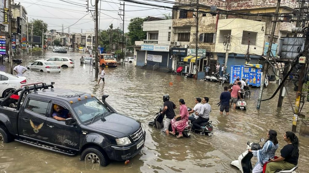  Commuters make their way through a waterlogged road following rainfall, in Patiala (Credit: PTI)