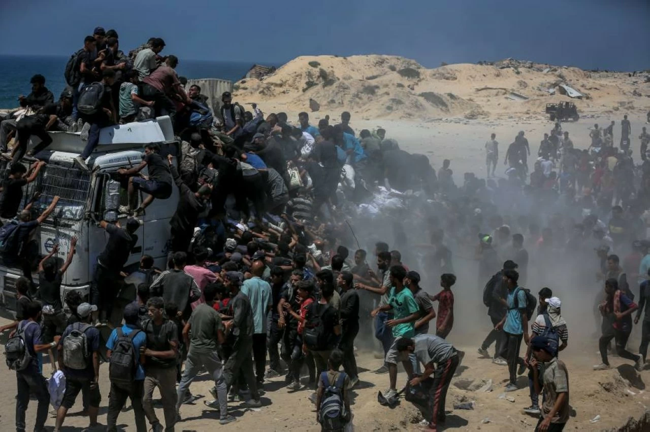 Palestinians walk for kilometers after receiving flour aid distributed from trucks that entered the Zikim area, a kibbutz in southern Israel, amid ongoing Israeli attacks and severe food shortages, in Gaza City, Gaza, on July 27, 2025. (Photo by Saeed M. M. T. Jaras/Anadolu via Getty Images)