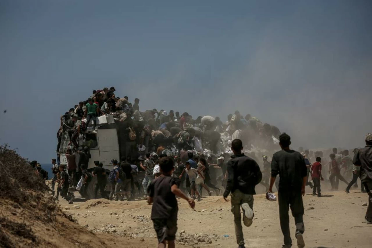 Palestinians walk for kilometers after receiving flour aid distributed from trucks that entered the Zikim area, a kibbutz in southern Israel, amid ongoing Israeli attacks and severe food shortages, in Gaza City, Gaza, on July 27, 2025. (Photo by Saeed M. M. T. Jaras/Anadolu via Getty Images) 