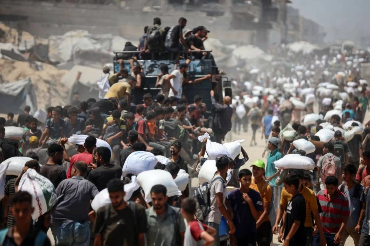Palestinians gather at aid distribution points, forming large crowds as they rushed to collect boxes and sacks of supplies as trucks transporting humanitarian aid enter Gaza from the Zikim area in the north following the Israeli army's announcement of a "tactical suspension" in Gaza City, Gaza on July 27, 2025. (Photo: Khames Alrefi/Anadolu via Getty Images)