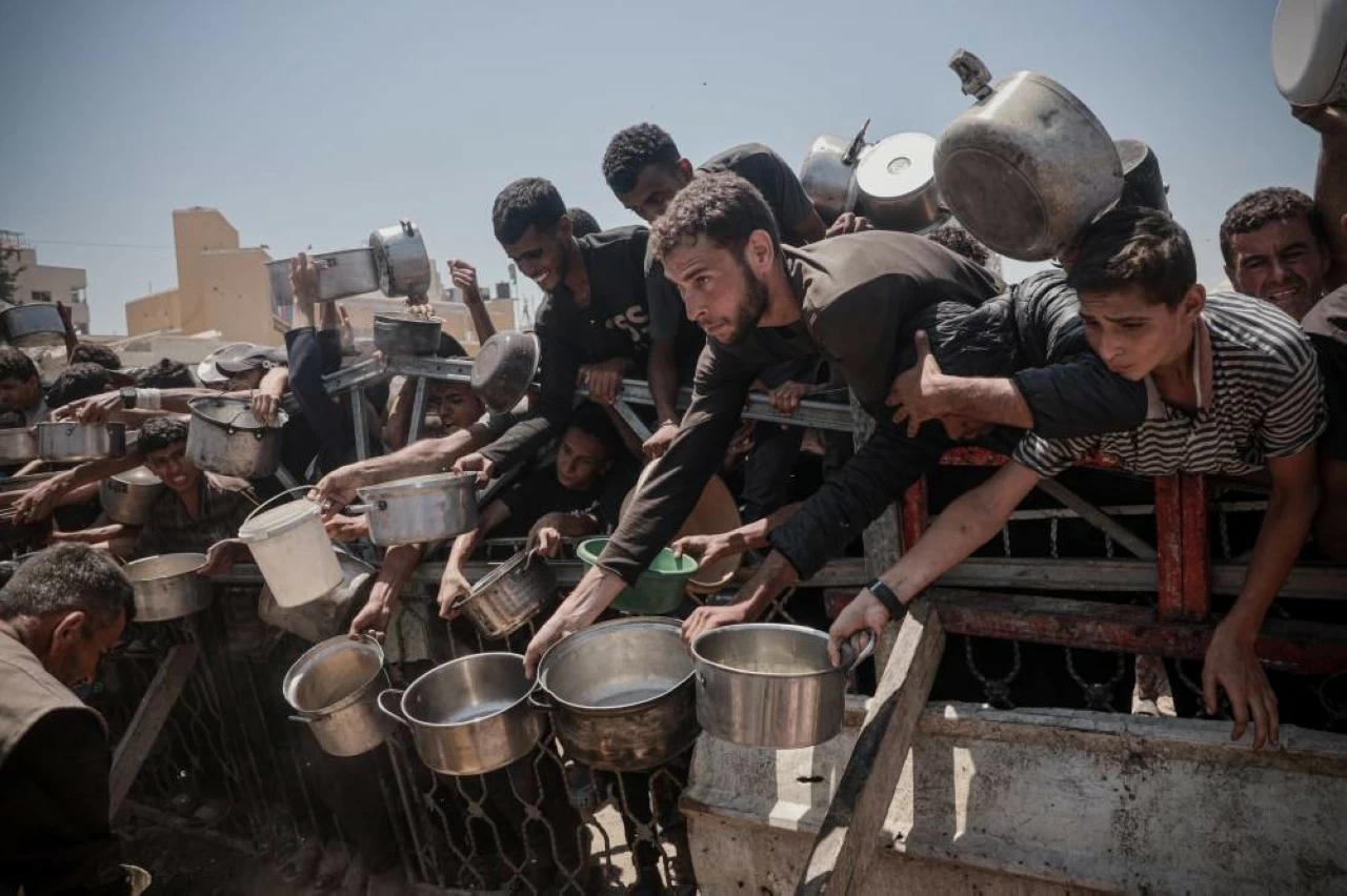 Hundreds of Palestinians struggling with hunger wait for hours under the scorching heat to receive food aid distributed by a charity organization as the deepening humanitarian crisis continue to severely impact Palestinians through widespread food shortages in Gaza City, Gaza on July 27, 2025. (Photo by Abdalhkem Abu Riash/Anadolu via Getty Images) 