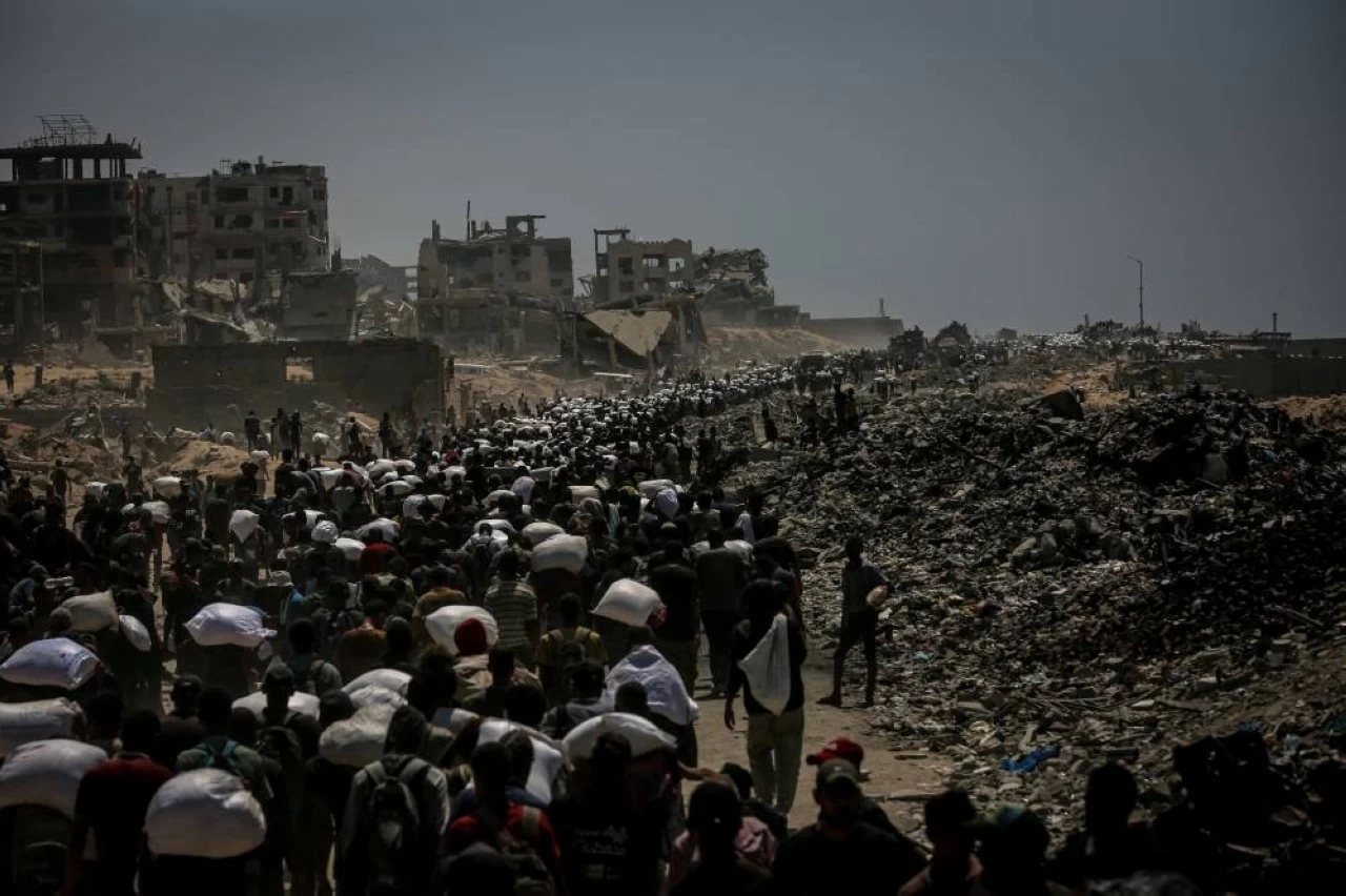 Palestinians walk for kilometers after receiving flour aid distributed from trucks that entered the Zikim area, amid ongoing Israeli attacks and severe food shortages, in Gaza City, Gaza, on July 27, 2025. (Photo by Saeed M. M. T. Jaras/Anadolu via Getty Images)