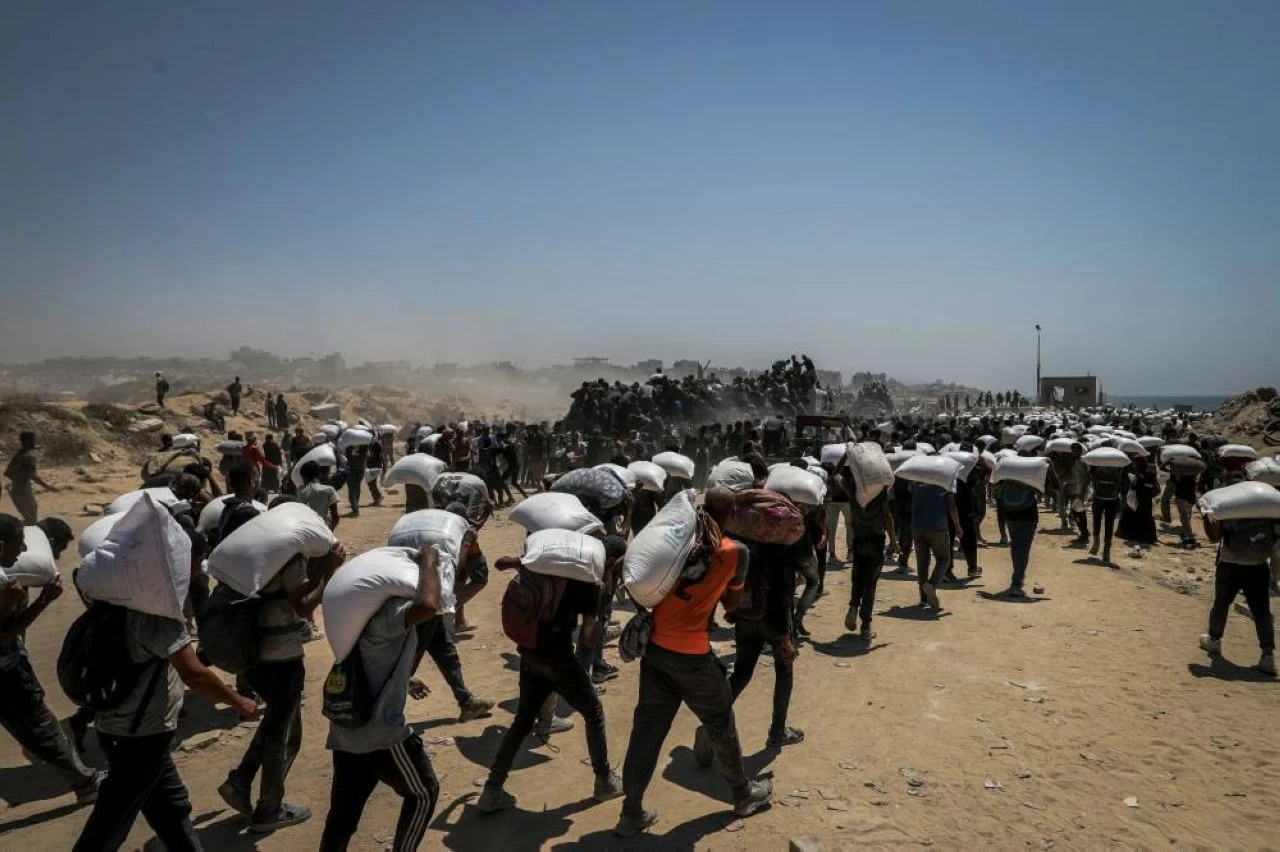 Palestinians gather at aid distribution points, forming large crowds as they rushed to collect boxes and sacks of supplies as trucks transporting humanitarian aid enter Gaza from the Zikim area in the north following the Israeli army's announcement of a "tactical suspension" in Gaza City, Gaza on July 27, 2025. (Photo: Khames Alrefi/Anadolu via Getty Images)