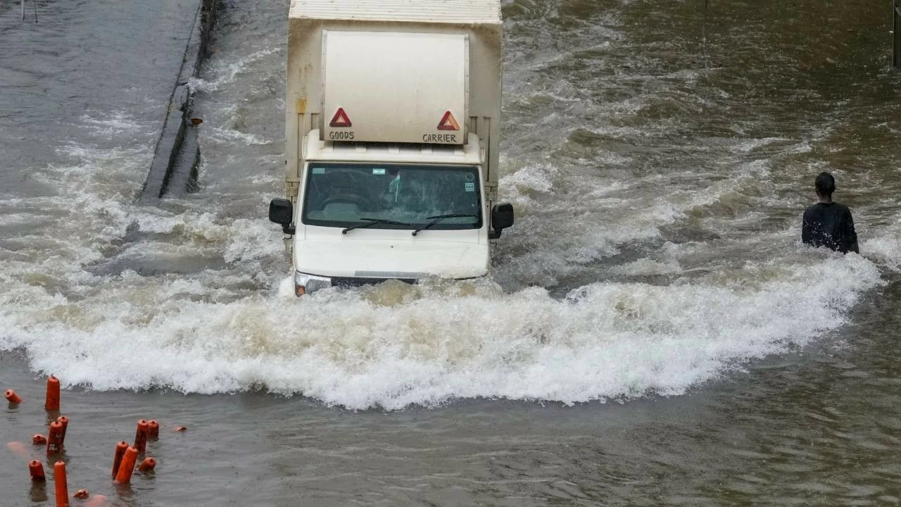 Commuters wade through a waterlogged road following rainfall at Sion in Mumbai on Tuesday. (PTI Photo)