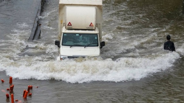 Commuters wade through a waterlogged road following rainfall at Sion in Mumbai on Tuesday. (PTI Photo)