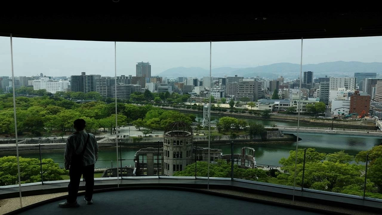 A man looks at the preserved Atomic Bomb Dome from an observation point near the Hiroshima Peace Memorial Park in Hiroshima, Japan, April 25, 2025.