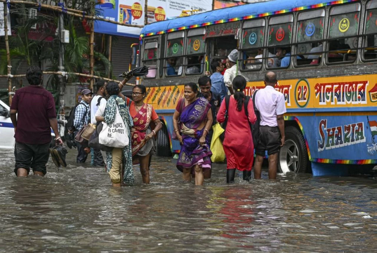 Commuters make their way through a waterlogged road after heavy rain in Kolkata