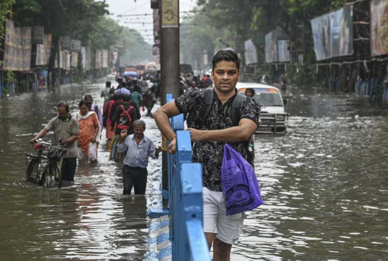  Commuters make their way through a waterlogged road following rain