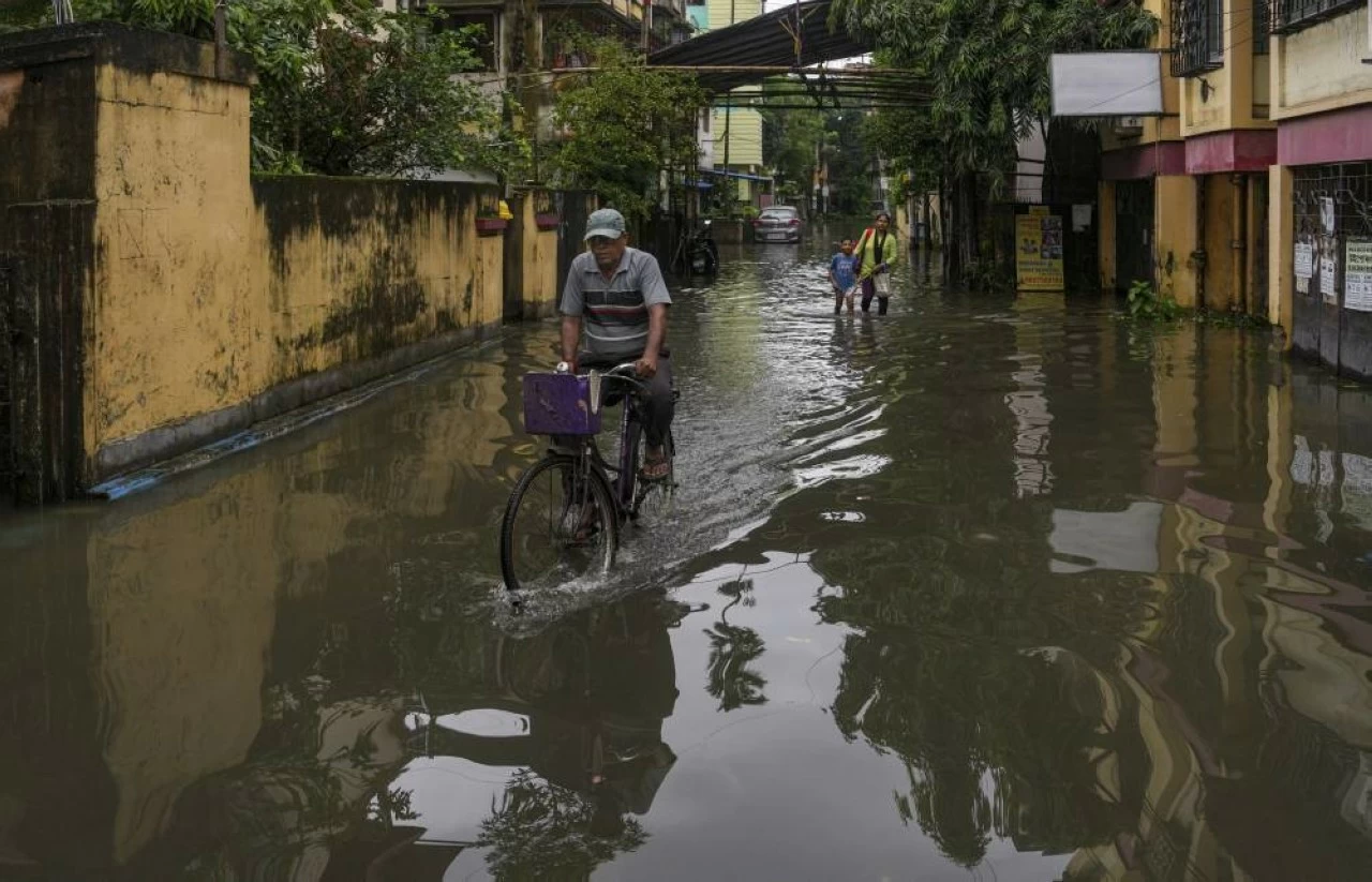 Commuters make their way through a waterlogged road following rain, in Kolkata,