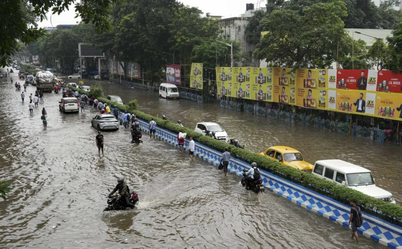 Commuters make their way through a waterlogged road following rain