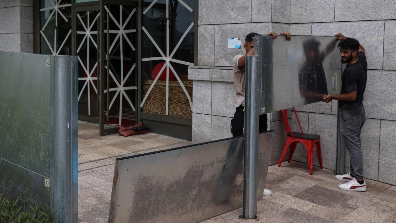 Workers install waterproof steel plates to protect against flooding from Super Typhoon Ragasa