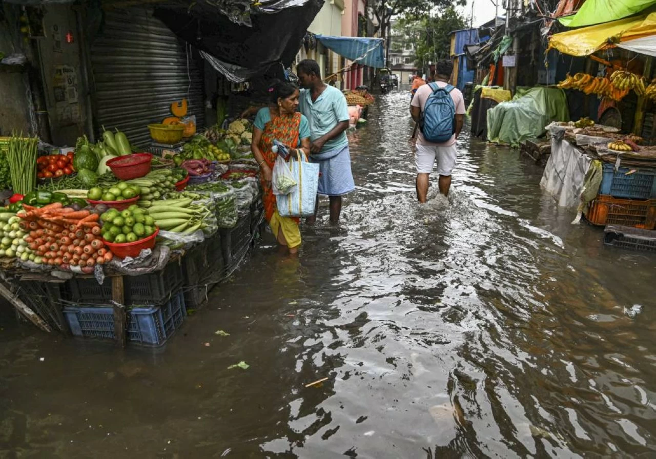 People make their way through a waterlogged market area following rain