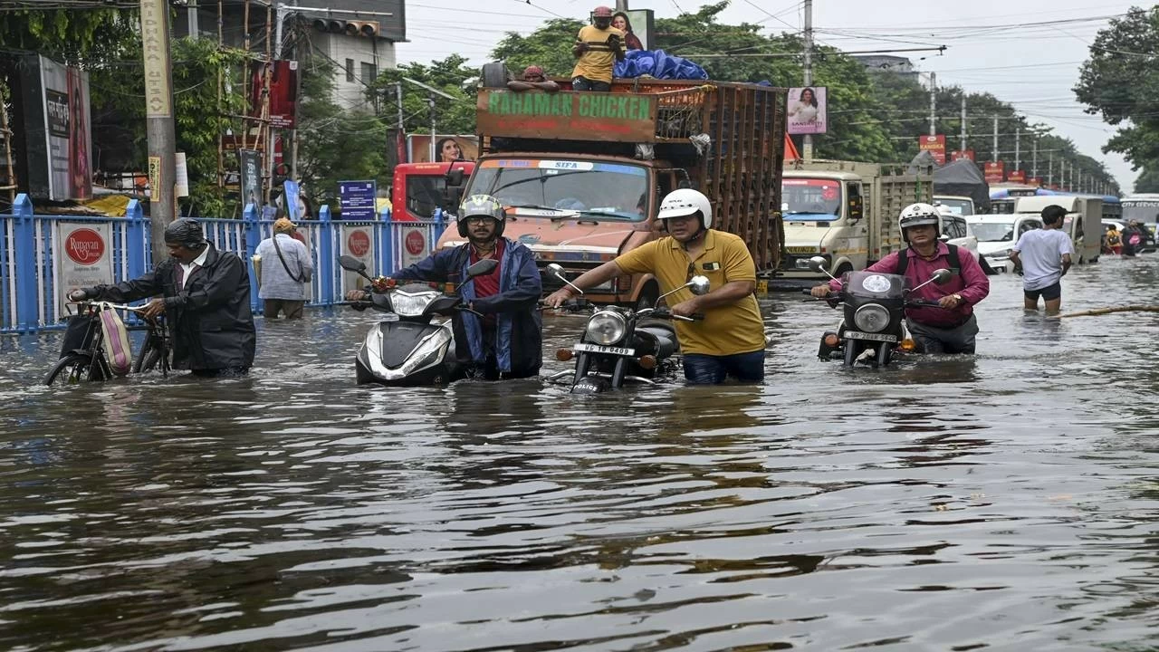 People make their way through a flooded road after heavy rainfall, in Kolkata, on Tuesday, Sept. 23, 2025. (PTI Photo)