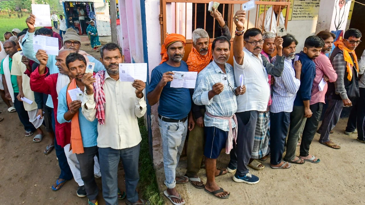 People show their credentials as they wait in a queue to cast votes at a polling station in Patna. The fate of candidates in 121 constituencies have been determined in the first phase of elections. (Photo credit: PTI)