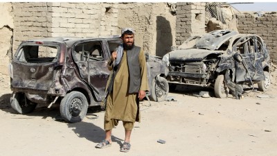 A Taliban fighter stands next to vehicles destroyed during an airstrike following a temporary ceasefire amid the conflict between Afghanistan and Pakistan