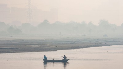 Men row a boat in the Yamuna river as a layer of smog engulfs the city amid deterioration in the air quality, in New Delhi
