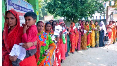 Voters wait in a queue to cast their votes at a polling booth during the second and final phase of the Bihar Assembly elections, in Katihar