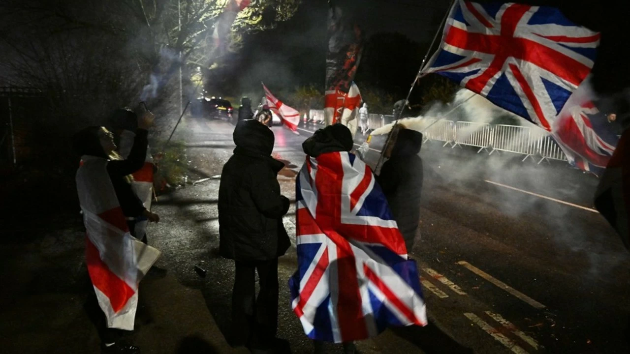 People protest with flags and banners outside The Bell Hotel after a court ruled migrants can stay at the Epping hotel in Epping, England.