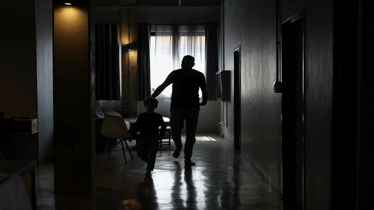 A Palestinian man, one of 130 granted entry to South Africa after initially being denied for not meeting immigration requirements, walks with his child to an undisclosed location in Johannesburg, South Africa, on November 14, 2025. (Photo Reuters)