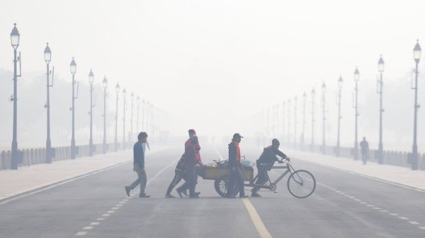  Workers push a cart across Kartavya Path during a smoggy winter morning, in New Delhi, Saturday, Nov. 22, 2025