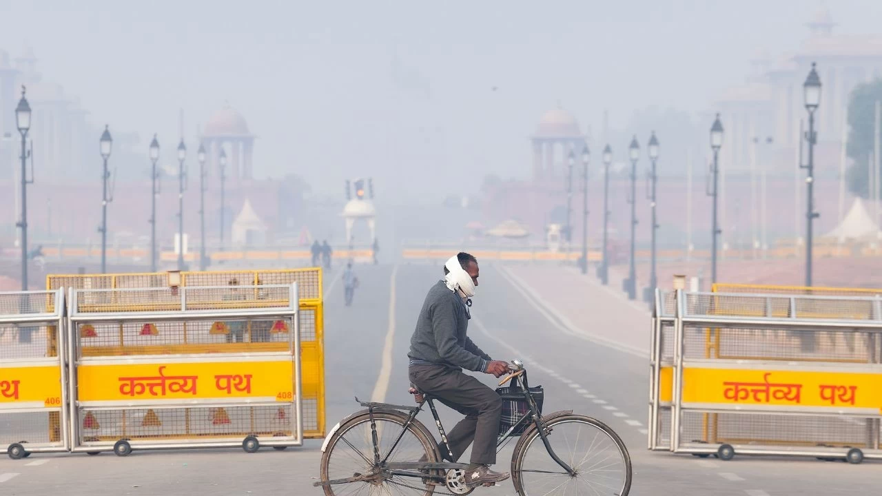 A commuter rides a bicycle during a smoggy winter morning, at Kartavya Path, in New Delhi
