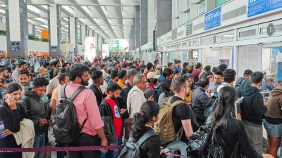 Stranded passengers wait in a queue at a counter after IndiGo cancelled more than 400 flights, at the Kempegowda International Airport, in Bengaluru, Karnataka