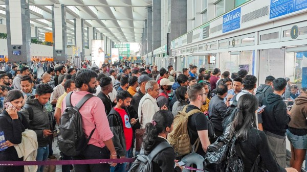 Stranded passengers wait in a queue at a counter after IndiGo cancelled more than 400 flights, at the Kempegowda International Airport, in Bengaluru, Karnataka
