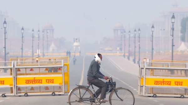A commuter rides a bicycle during a smoggy winter morning, at Kartavya Path, in New Delhi