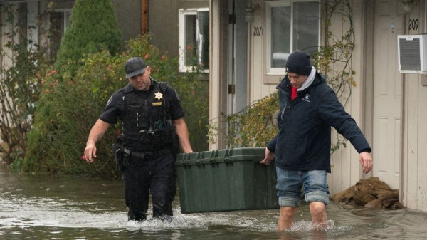 Deputy Sheriff Kalani Apilado helps Brandon Phasith carry belongings while evacuating amidst rising floodwater, as an atmospheric river brings rain and flooding to the Pacific Northwest, in Sultan, Washington