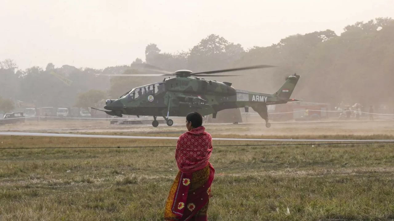 A helicopter takes off during rehearsal for Vijay Diwas commemorations at Kolkata’s Maidan, as a woman looks on from the ground during practice drills