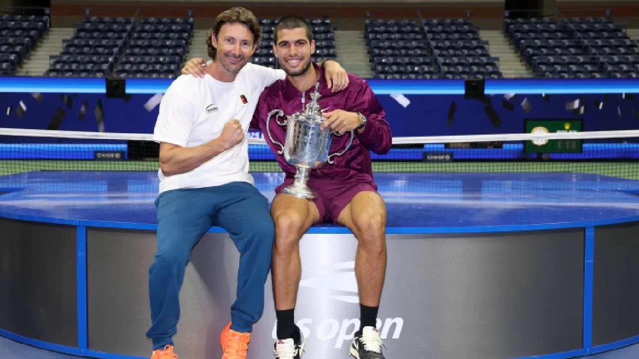 Carlos Alcaraz of Spain poses with his trophy next to his coach Juan Carlos Ferrero after defeating Jannik Sinner in US Open 2025 final in New York. 