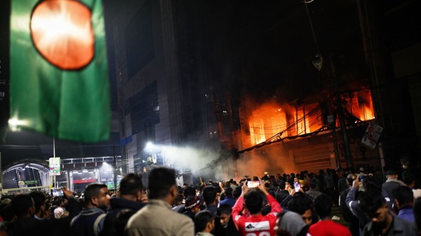 A crowd gathers near the premises of the Prothom Alo daily newspaper which was set on fire by angry protesters after news reached the country from Singapore of the death of a prominent activist Sharif Osman Hadi 