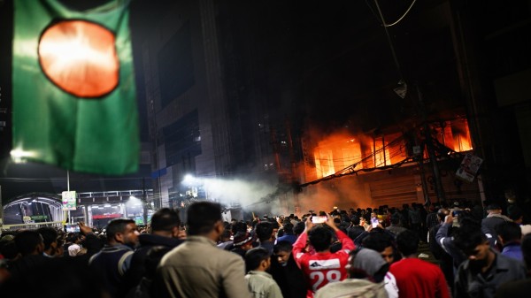 A crowd gathers near the premises of the Prothom Alo daily newspaper which was set on fire by angry protesters after news reached the country from Singapore of the death of a prominent activist Sharif Osman Hadi, in Dhaka, Bangladesh, on Friday, Dec. 19, 2025. (AP/PTI)