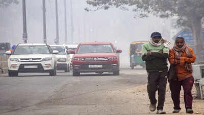 People walk along the roadside amid low air quality on a winter morning, in Gurugram, Sunday, Dec. 21, 2025. (PTI Photo)