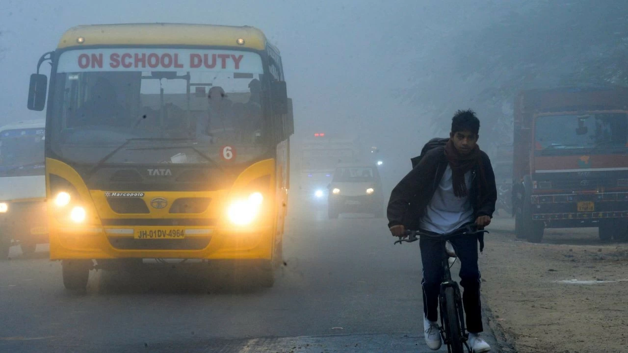 Vehicles make their way through dense fog on a cold winter morning, in Ranchi 