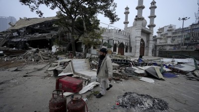 A man walks past belongings lying on a road after the demolition of alleged encroachments at Turkman Gate area, in New Delhi, (PTI Photo/Shahbaz Khan)