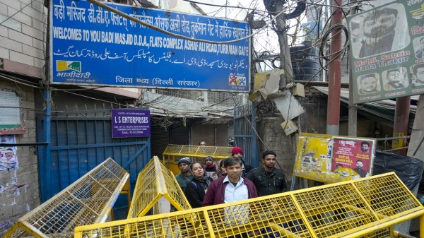 People stand at the entrance of a street closed with barricades after a demolition drive of alleged encroachments at Turkman Gate area, in New Delhi. (PTI Photo/Shahbaz Khan)
