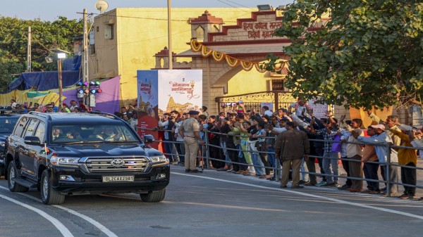Prime Minister Narendra Modi greets people as his convoy proceeds towards the VVIP circuit house after his arrival, in Veraval, Gir Somnath district, Gujarat. 