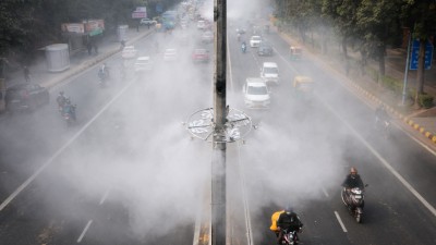 Vehicles drive past anti-smog misting system installed on a road to control air pollution in New Delhi. (Photo credit: Reuters)
